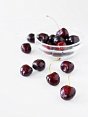 Cherries in a glass bowl and scattered around the table