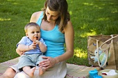 Baby eating carrot at picnic with mother