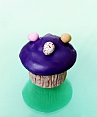 Muffin with purple icing and chocolate eggs