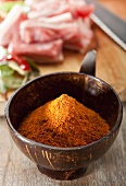 Curry Nihari Gewürzmischung in einer Schale, im Hintergrund Lammfleisch