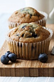 Two blueberry muffins on chopping board