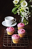 Muffins with strawberry cream, cup and saucer and vase of flowers
