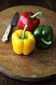 Yellow, red and green peppers on chopping board