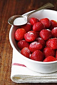 Sugared strawberries in a bowl on a tea towel