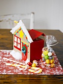 Christmas sweets and cardboard house on table mat