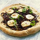 Whole pizza topped with red onions and goat's cheese