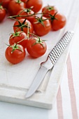 Cherry tomatoes on chopping board with knife