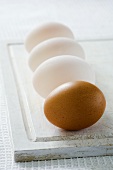 Three duck eggs and a hen's egg on chopping board