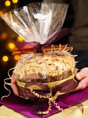 Hands holding gift-wrapped panettone