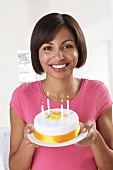 A woman holding a birthday cake