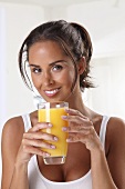 An athletic woman holding a glass of orange juice
