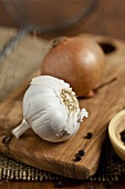 Garlic, onion and peppercorns on a chopping board