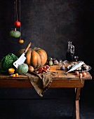 An arrangement with pumpkin, vegetables, pomegranate and fish