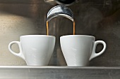 Espresso flowing into two cups