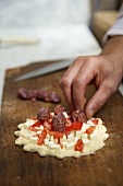 Manakish being topped with sausage (Lebanon)