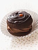 A chocolate whoopie pie with icing and chocolate buttons