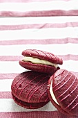 Three raspberry whoopie pies on a striped cloth