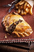 Medium steak pasty (pastry, England), sliced open, with French fries
