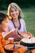 Mother and son with birthday cake in garden