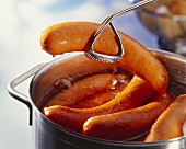 Sausages being removed from a pot