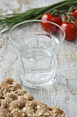 A glass of water, crispbread, tomatoes and chives