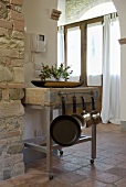 Trolley out of stainless steel and large wooden tray in the lfoyer of a mediterranean country home