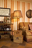 Two piece basket set in front of a floor lamp next to a sofa and wallpaper with an orange and white striped pattern