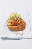 A crostino topped with tomato tapenade and bean sprouts