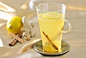 A glass of ginger tea with lemons and cinnamon