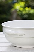 An empty white bowl on a table outside