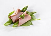 Asparagus and ham rolls on spinach leaves