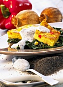Milk and corn cakes on a bed of spinach with poppy seed yogurt