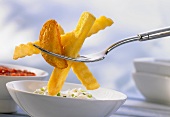 Frozen chips on a fork with a chive dip