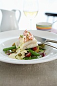 Fish fillet and prawns on potato salad with vegetables