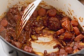 Veal bones being stirred into tomato puree