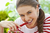 A young woman biting into a red chilli pepper