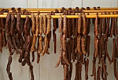 Assorted hard-cured sausages hanging on rods