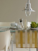 A dining table with a table runner, a carafe, a vase and Romanesco broccoli