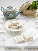 Tofu slices, tofu cubes, tea pot, bamboo steamer with paksoi