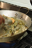 Sauteeing and turning shrimp in a pan