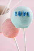 A light blue cake pop with the word 'Love' and a pink cake pop