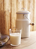 A glass of a milk and a milk churn