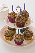 Chocolate cupcakes with candles on a cake stand