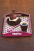 A stuffed chocolate rabbit and coffee on a tray