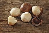 Macadamia nuts, with and without shells on a wooden surface