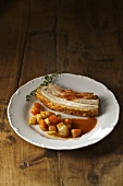A slice of roast pork with root vegetables