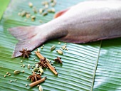 A fresh red snapper and spices on a banana leaf
