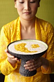 Frau serviert Kokospudding mit Tapioka und Ananas (Indonesien)
