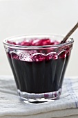Blueberry jam in a glass bowl with a spoon