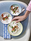 A hand taking a bowl of chicken and coconut soup (Thailand)